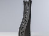 sculpture représentant un bloc de bois noir incurvé posé sur une surface blanche