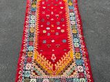a red rug with fringes on the ground
