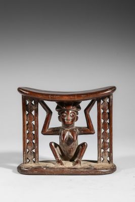 une petite sculpture en bois représentant un homme assis sur un tabouret