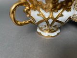 a white and gold vase with a gold handle