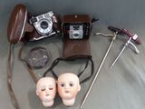 un appareil photo, un casque audio, une paire de lunettes, une paire de ciseaux et deux têtes de poupées
