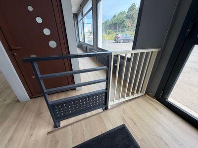 une barrière de sécurité pour bébé placée devant une porte, avec un paillasson noir