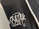 a close up of a black hoodie with a white logo on it