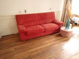 un canapé rouge placé dans un salon près d'une fenêtre