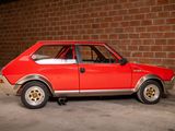 a red car that is parked in front of a brick wall