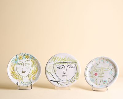 trois assiettes ornées de dessins sont posées sur une table