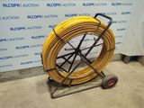 an image of a yellow hose is on a cart in front of a wall