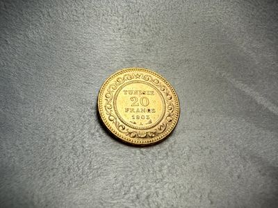 a close up of a gold coin on a gray surface
