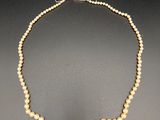 un collier de perles blanches avec un fermoir en or