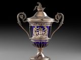 un vase argenté et bleu surmonté d'un oiseau