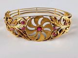 une image représentant un bracelet en or orné de pierres roses sur un fond blanc