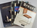 trois livres posés sur une table blanche, avec une chaise et un vase
