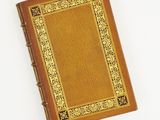 un vieux livre à la couverture dorée posé sur une surface blanche