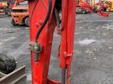 the back end of a red excavator sitting on top of a parking lot