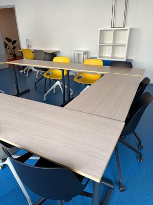 des tables et des chaises dans une pièce avec une moquette bleue et des chaises jaunes