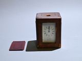 a small wooden clock sitting next to a small piece of paper