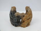figurines représentant deux personnes assises sur une surface blanche, sur fond blanc