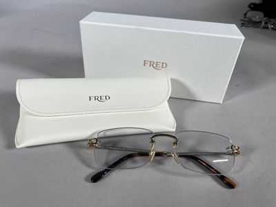 une paire de lunettes et son étui posés sur une table à côté d'une boîte blanche