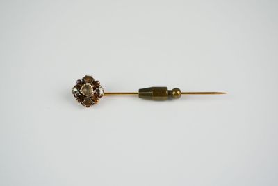 a close up of a metal pin with a flower on it