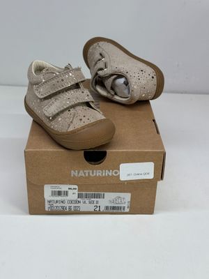une paire de chaussures pour bébé dans une boîte posée sur une surface blanche