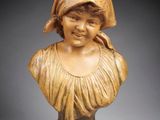 carved bust of a young girl with a bonnet on her head