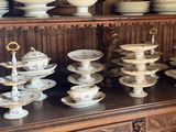 many plates and bowls on the top of a china cabinet