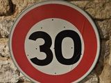 une photo d'un panneau de limitation de vitesse sur un mur en pierre