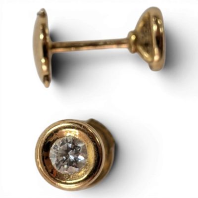 two pairs of gold and diamond stud earrings on a white surface