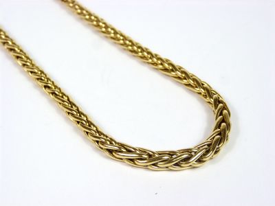 gros plan d'un collier en or sur une surface blanche