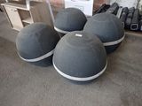 trois boules grises posées sur le sol, à côté d'une étagère en bois