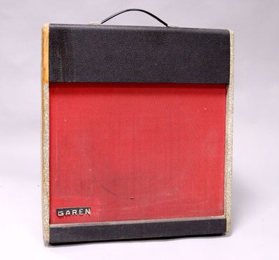 a red and black guitar amplifier sitting on a white surface