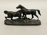 une statue en bronze représentant deux chevaux au galop sur une colline