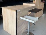a counter with a stool and a shelf in the background