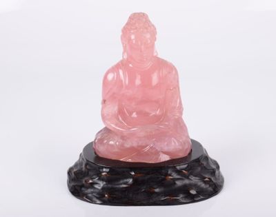 Statue de Bouddha en jade rose sur un socle en marbre noir, sur fond blanc