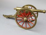 a red and gold cannon sitting on a white surface