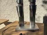 two coffee machines on a table with a cup on it