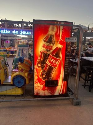 un distributeur automatique sur lequel figure une publicité pour Coca-Cola