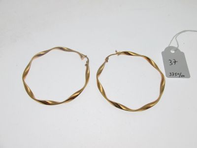 deux boucles d'oreilles en anneau dorées avec une étiquette de prix sur un fond blanc