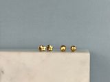 deux boucles d'oreilles en or posées sur un bloc de marbre blanc