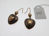 une paire de boucles d'oreilles ornées d'un cœur, posée à côté d'une étiquette de prix