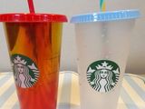 two starbucks cups with straws sitting on a table