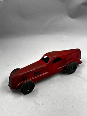une petite voiture rouge posée sur une surface blanche