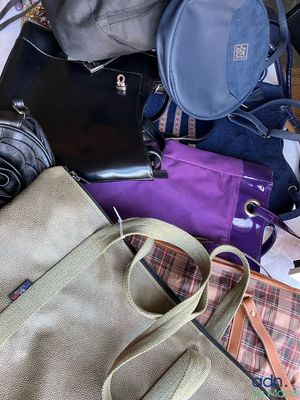 une pile de sacs à main et de sacs à bandoulière posée par terre