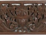 carved wood panel with a vase on top of it on a white surface