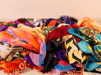 un tas d'écharpes de toutes sortes posées sur un canapé blanc