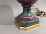 a purple vase on a gold stand on a white table