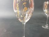 two wine glasses with gold designs on them on a table