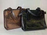 two different colors of handbags sitting side by side on a white surface