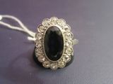 an image of a ring with a large black stone surrounded by small white diamonds
