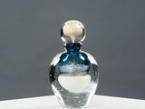 une photo d'un flacon de parfum posé sur une table blanche
